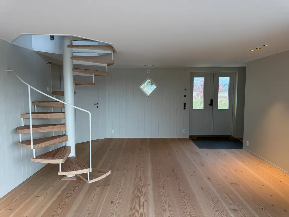 Nyrenoverat trähus med vit spiraltrappa i furu — KAAB Bygg